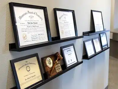 Display shelf showing framed dental certificates, awards, and professional credentials for Moorhead Dental Associates.