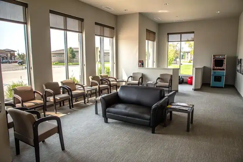 Modern dental office waiting room with comfortable seating, large windows, and contemporary décor.