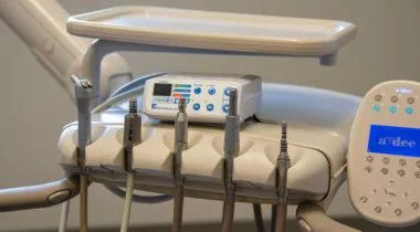 Dental equipment and control panels mounted on wall in clinical treatment room setting.